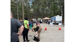 A group of people, some with pets, gather among tents