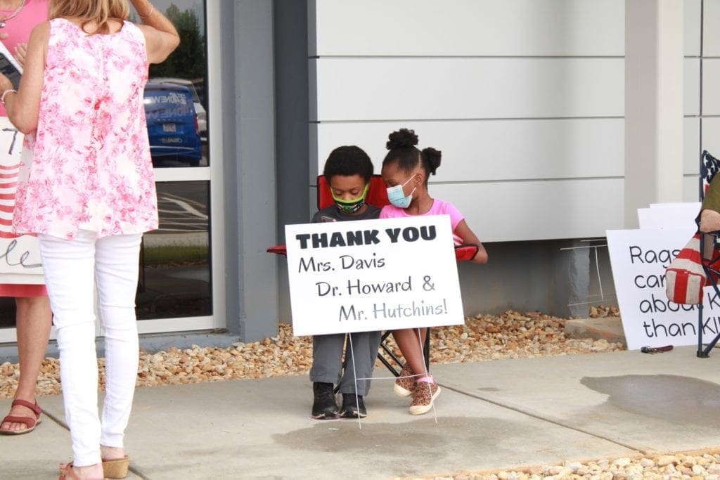 Two children holding sign with thanks to the three Black school board members
