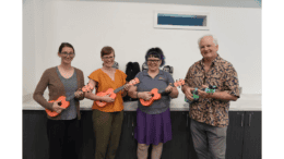 Three women and a man playing ukuleles